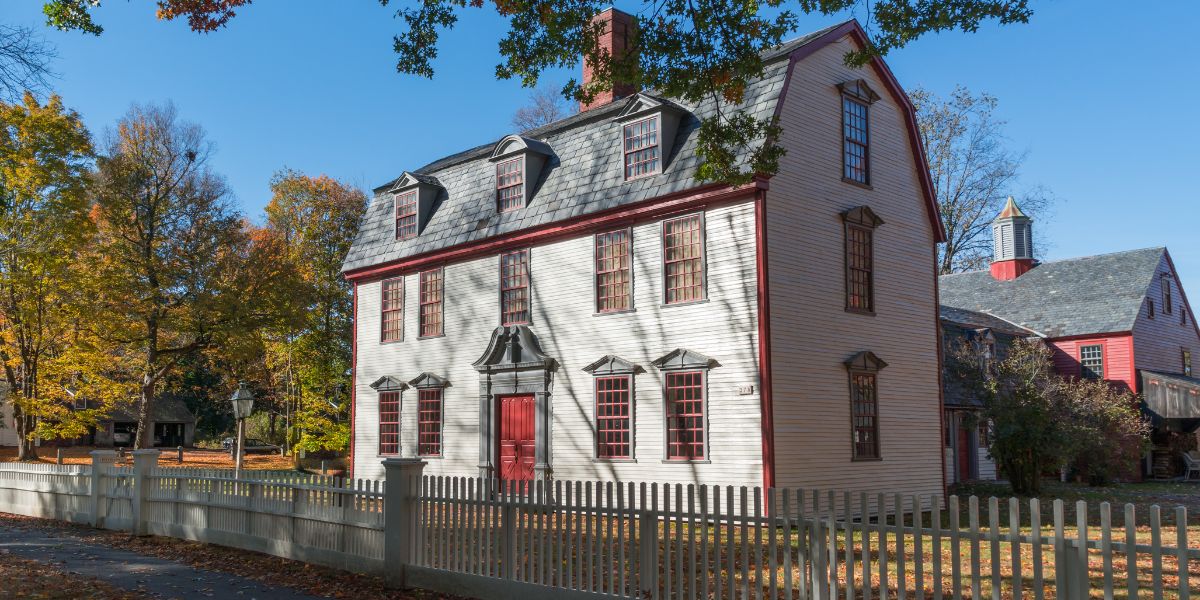 Colonial-style house with red trim and picket fence.