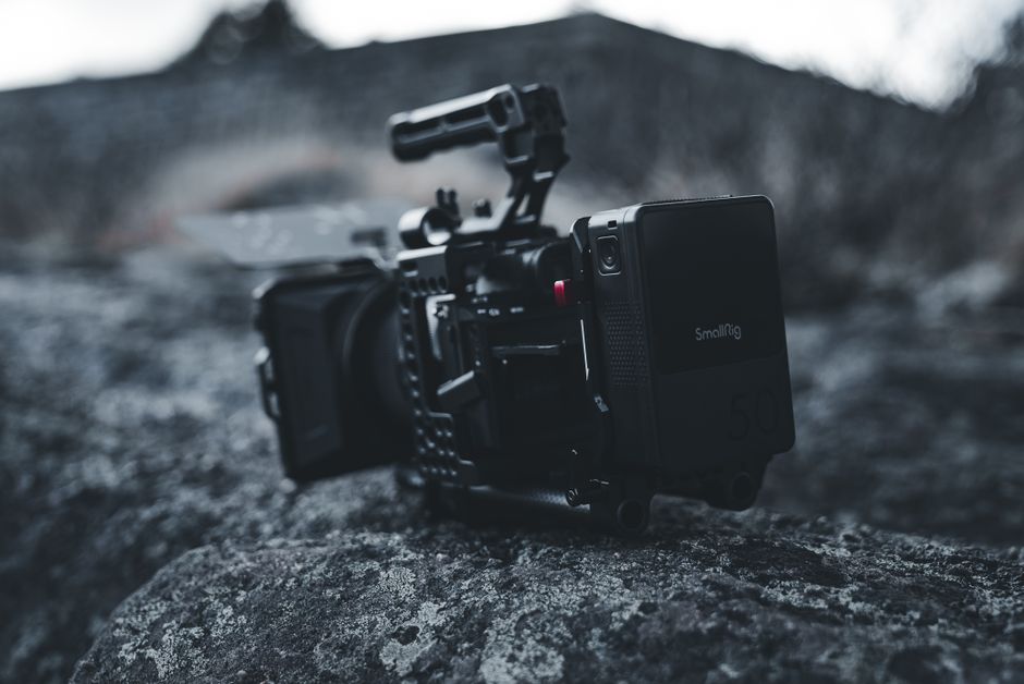 A professional DSLR camera sitting in a damp, foggy outdoor setting, with droplets of condensation on its body, symbolizing the threat of a high-humidity environment to camera gear.
