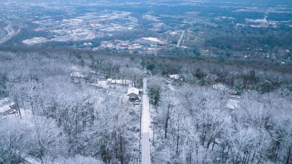 A scenic view of residential homes dotting the green, rolling hills of Chattanooga, Tennessee, under a clear sky.