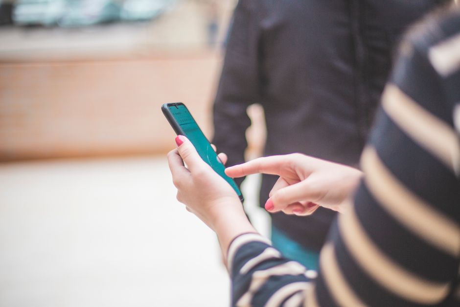 A close-up of a hand holding a smartphone showing a map with a location pin on a modern house, representing a property listing found via local search.
