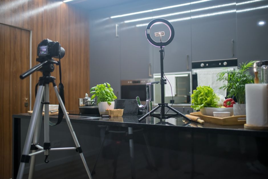 Professional camera on a tripod is set up in a bright, modern living room, perfectly positioned for a real estate photogra...