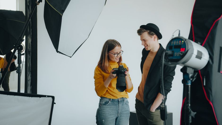 A professional photographer in a modern home checks the back of their camera screen, reviewing shots to ensure quality and efficiency during a real estate shoot.